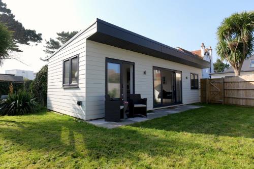 a small white house with a black roof at Villa Maria Southbourne - 2 Mins to Beach - Coastal - Dog-Friendly - Modern Luxury - Large Private Garden - Private Access - Parking in Southbourne