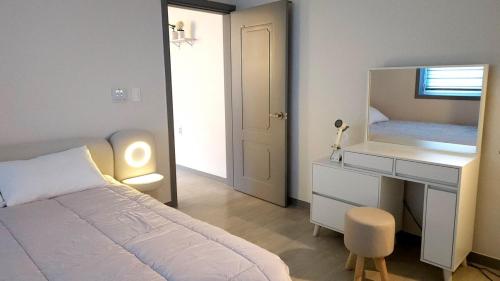 a bedroom with a bed and a desk and a mirror at Pine-tree stay Mini in Samgong