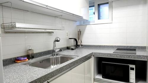 a kitchen with a sink and a microwave at Pine-tree stay Mini in Samgong
