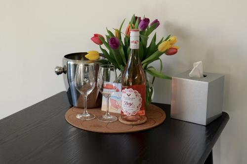 a bottle of wine and glasses on a table with flowers at Villa Maria Southbourne - 2 Mins to Beach - Coastal - Dog-Friendly - Modern Luxury - Large Private Garden - Private Access - Parking in Southbourne