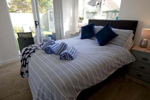 a bed with blue pillows on it in a bedroom at Villa Maria Southbourne - 2 Mins to Beach - Coastal - Dog-Friendly - Modern Luxury - Large Private Garden - Private Access - Parking in Southbourne