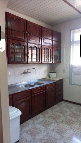 a kitchen with wooden cabinets and a sink at staylikehome guesthouse in Nieuw Nickerie