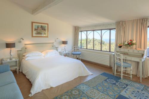 a bedroom with a bed and a desk and a window at Le Jas de Gordes in Gordes