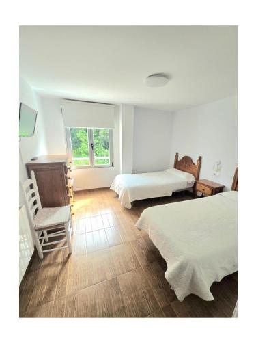 a bedroom with two beds and a chair and a window at Pension Villa ** in Comillas