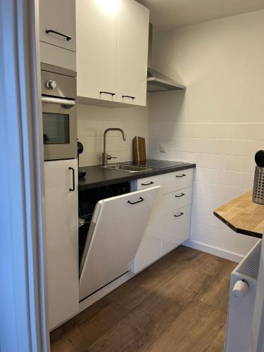 a kitchen with white cabinets and a sink at Parkzicht Zwanenburg in Zwanenburg