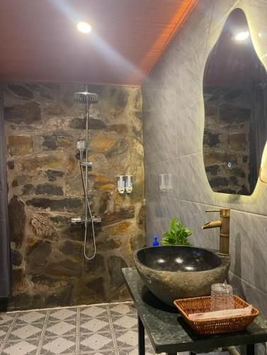 a bathroom with a sink and a stone wall at Flora Garden Homestay in Xuân Sơn