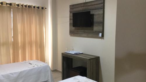 a room with a table and a tv on the wall at Open Hotel in Telêmaco Borba