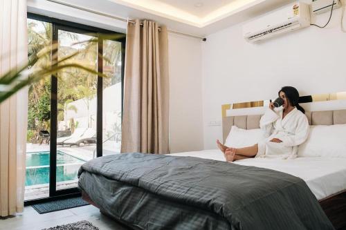a woman sitting on a bed talking on a cell phone at White Tiger Villa in Goa