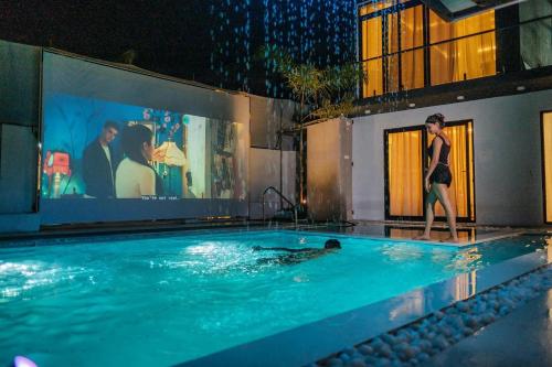 a woman walking in a swimming pool at night at White Tiger Villa in Goa