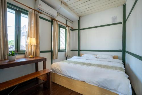 a bedroom with a green and white bed and windows at Barn Laos Hostel in Vientiane