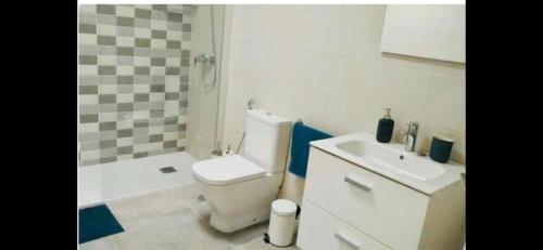 a bathroom with a white toilet and a sink at CASA IBON 1A pool view Playa Roca in Costa Teguise