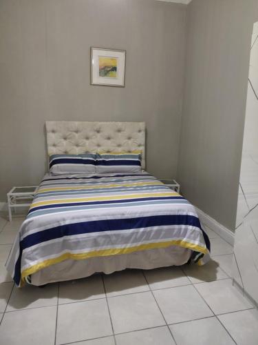 a bedroom with a bed with a striped blanket at Ocean River in Gqeberha