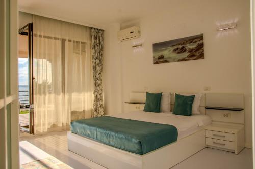 a white bedroom with a bed with green pillows at RoApart Riva Lake Studiouri si Apartamente 2-3 camere cu vedere lac -parcare privata in Mamaia