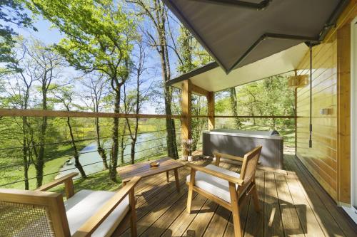 a screened in porch with a table and chairs on a deck at Les cabanes du Lac in Sévignac-Thèze