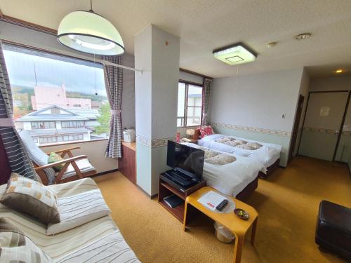a living room with two beds and a tv at Kofukan in Myoko