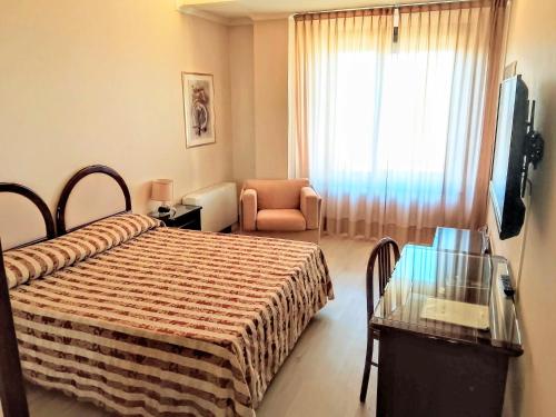 a hotel room with a bed and a chair and a window at Balletti Palace Hotel in Viterbo