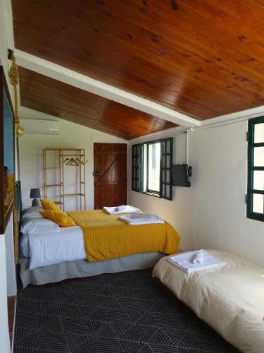 two beds in a room with a wooden ceiling at New Village in Vila Nova da Baronia