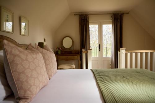 a bedroom with a bed with pillows and a window at Great Ashley Farm Holiday Cottage & Shepherds Huts in Bradford on Avon