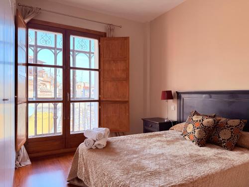 a bedroom with a bed and a large window at Smartmonki Sinagoga entre la Catedral y Zocodover in Toledo