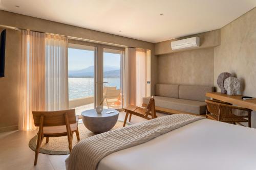 a bedroom with a bed and a view of the ocean at Beau Rivage Suites in Lóngos