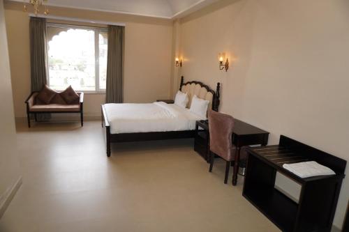 a bedroom with a bed and a desk and a piano at Neendar Heritage Resort in Jaipur