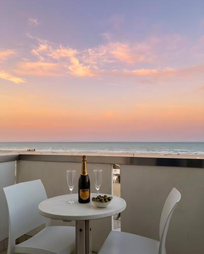 a table with a bottle of wine and two glasses at Hotel Columbia Frontemare in Rimini