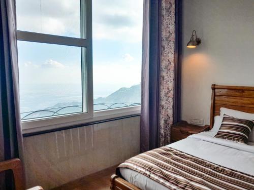 a bedroom with a bed and a large window at The Three Oaks Boutique Hotel in Mussoorie