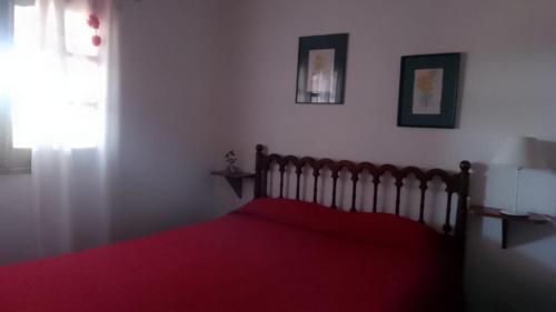 a bedroom with a red bed with a red blanket at cabaña La Retama in Villa Yacanto