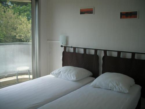 a bed with two pillows sitting next to a window at Arcachon Plage Pereire in Arcachon