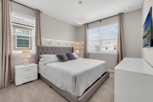 a bedroom with a bed and two windows at 9 BD 6.5 BA Solara Resort 9028 FK in Orlando