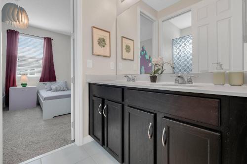 a bathroom with a sink and a large mirror at 9 BD 6.5 BA Solara Resort 9028 FK in Orlando
