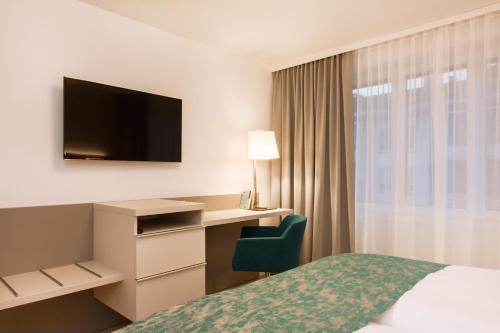 una camera d'albergo con un letto, una scrivania e una televisione di CITY STAY - Lindenstrasse a Zurigo