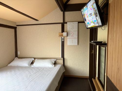 a bedroom with a bed and a tv on the wall at 指宿古民家宿 in Ibusuki