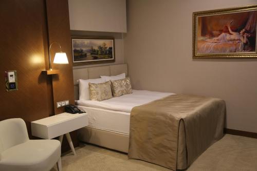 a small bedroom with a bed and a chair at Vivaldi Park Hotel in Ankara