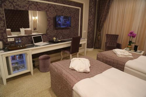 a hotel room with two beds and a desk with a mirror at Vivaldi Park Hotel in Ankara