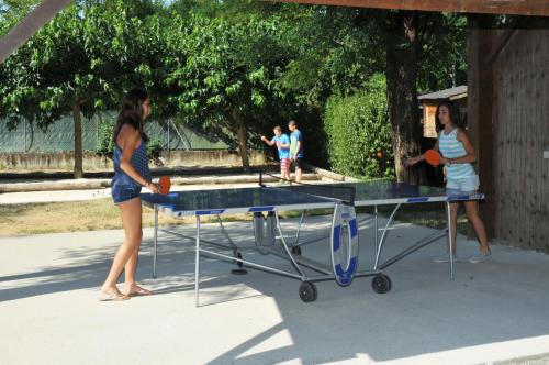 two women playing a game of ping pong at Camping Le Coin Charmant in Chauzon