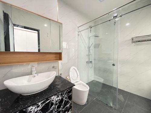 a bathroom with a sink and a shower and a toilet at QV Manor - Homestay kề biển Bình Sơn in Phan Rang–Tháp Chàm