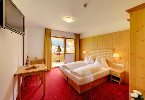 a hotel room with a large bed and a window at Helmhotel in San Candido