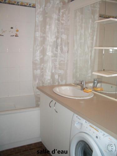 a bathroom with a sink and a washing machine at Arcachon Plage Pereire in Arcachon