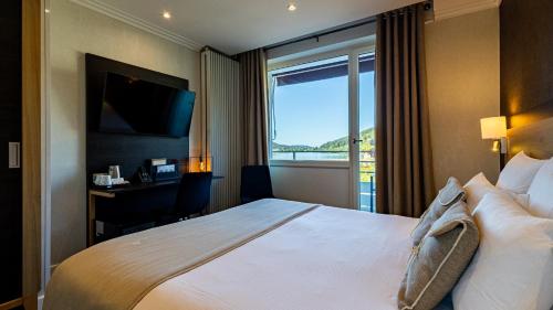 a hotel room with a large bed and a window at Hôtel Beau Rivage in Gérardmer