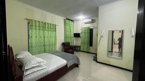 a bedroom with a bed with green curtains and a mirror at Hotel SIDAPORE in Lamobuang