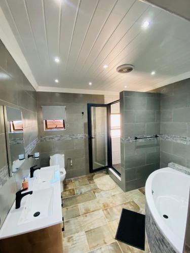 a bathroom with two sinks and a tub and a shower at Redem House in Modimolle