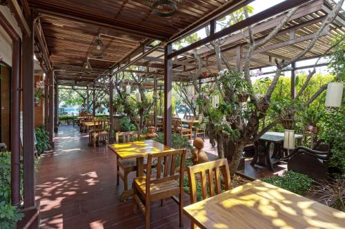 a restaurant with wooden tables and chairs and trees at Asia Hotels Group (Poonpetch Chiangmai) in Chiang Mai
