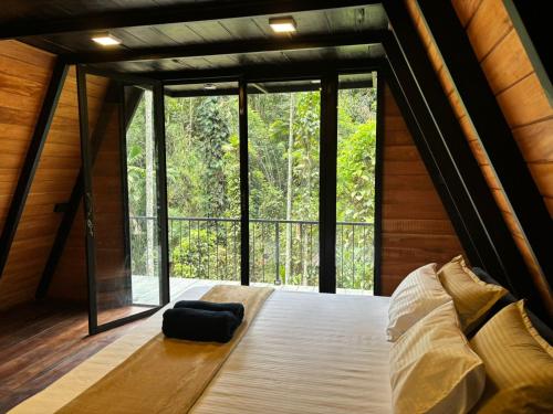 a bedroom in a tree house with a large window at Pepper Trails Riverstone in Polwattekanda