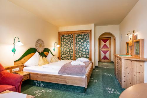 a bedroom with a large bed and a red couch at Wellnesshotel Mitterwirt in Dienten am Hochkönig