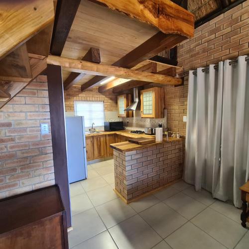 a kitchen with a white refrigerator and a brick wall at DuckPond Lodge Cottage in Oudtshoorn