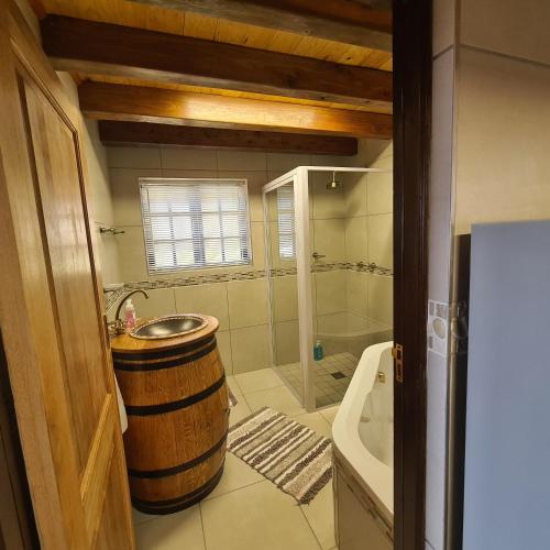 a bathroom with a barrel sink and a bath tub at DuckPond Lodge Cottage in Oudtshoorn