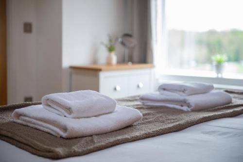 three towels are stacked on top of a bed at Modern 1 Bed - Beams - Parking in Stamford