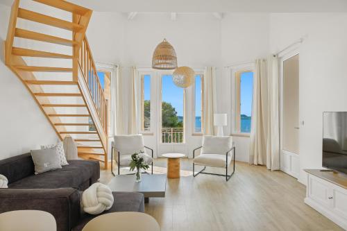 a living room with a staircase and a couch and chairs at Duplex d'exception face à la mer in Hyères