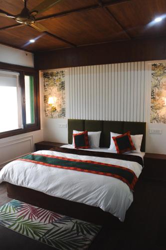 a bedroom with a large bed with colorful pillows at The Himalayan Roots in Kulu